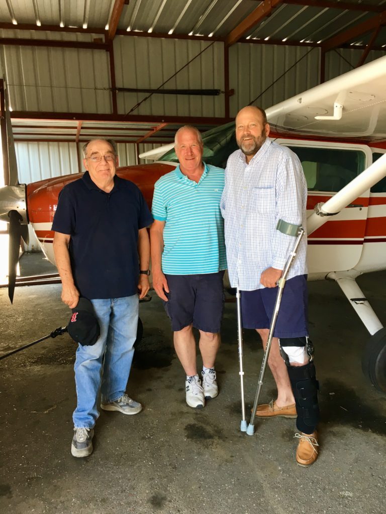 Pete with his buddies, Mike and Rex, in his hanger, next to his Cessna 182.